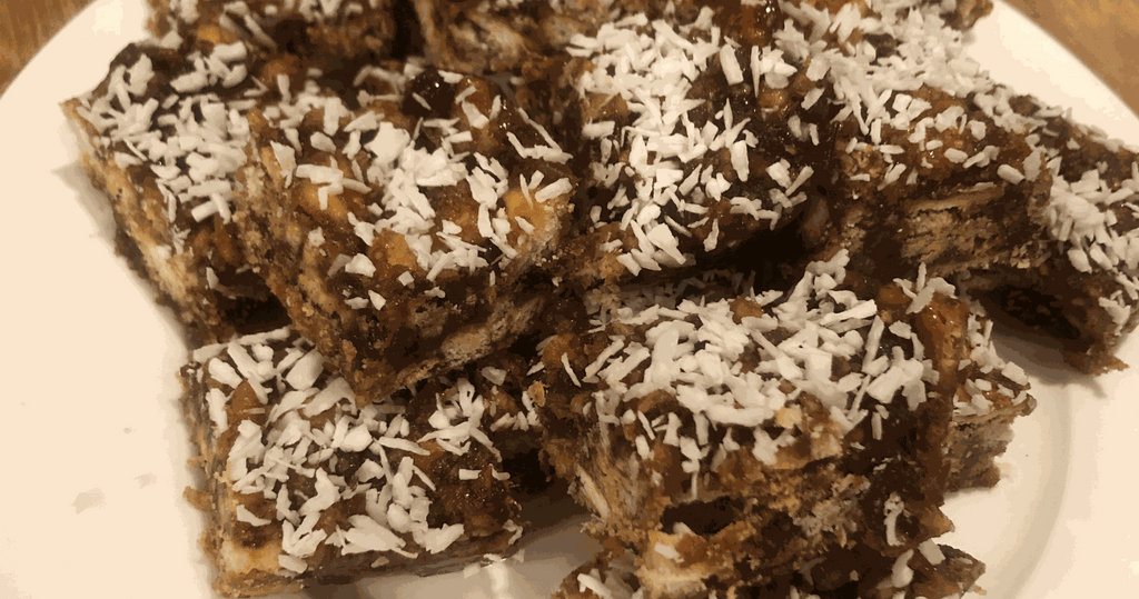 Unbaked South African date squares covered in desiccated coconut on a plate