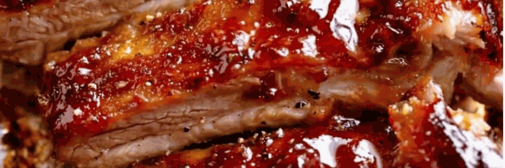 Sticky glazed BBQ pork ribs on a platter with barbecue sauce