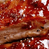 Sticky glazed BBQ pork ribs on a platter with barbecue sauce