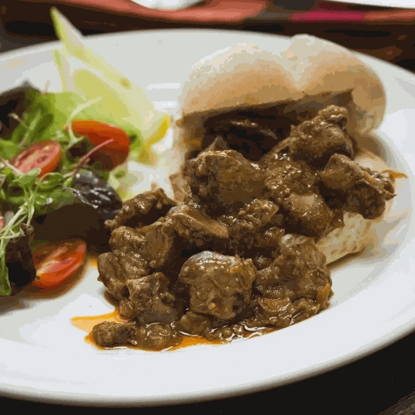 Peri-Peri coated meat with a roll and salad, showcasing Ina Paarman Coat & Cook Sauce.