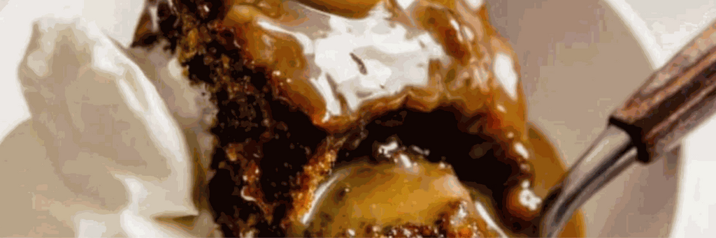 Moist sponge-like sticky toffee pudding topped with rich toffee sauce and served with cream
