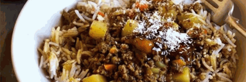 South African curry served with rice, chutney, and sliced bananas on a plate