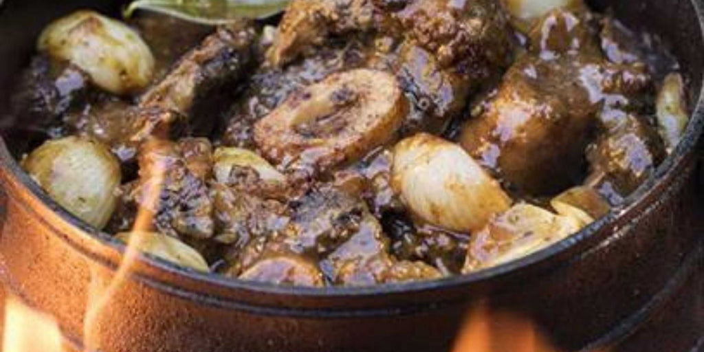 Traditional South African shin and oxtail beef potjie cooked over campfire with rich sauce and spices