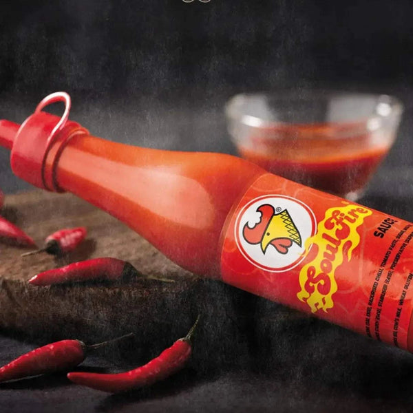 Chicken Licken Soulfire Hot Sauce 100ml bottle with red chili peppers and sauce bowl, spicy South African flavor
