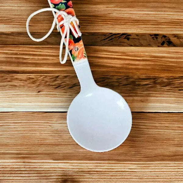 Enamel printed sugar spoon with black floral design and wooden handle