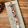 Enamel printed sugar spoon with black floral design and wooden handle