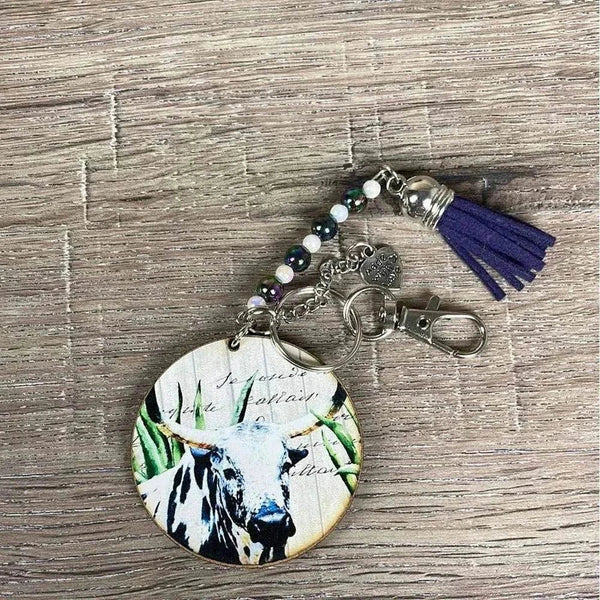 Wooden circle key tag with white and black cow design and navy tassel, 50mm size